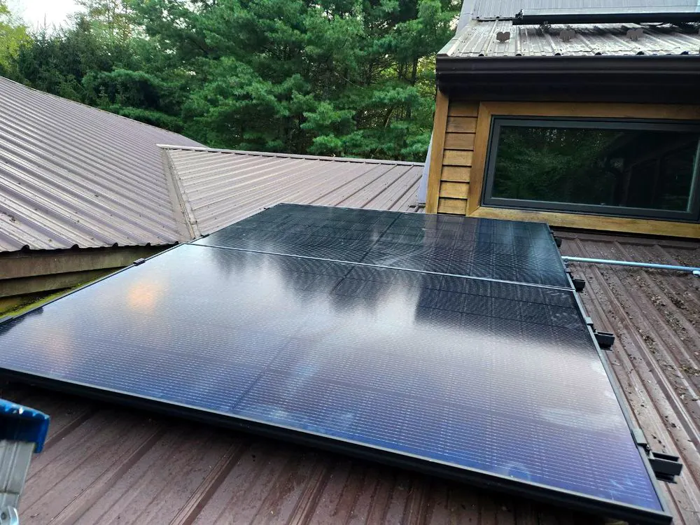 Solar modules clamped to a standing-seam metal roof beside a skylight