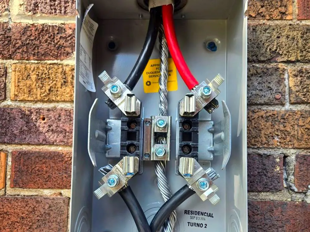 An electric meter socket opened during a service replacement, with the service entrance conductors landed on the lugs