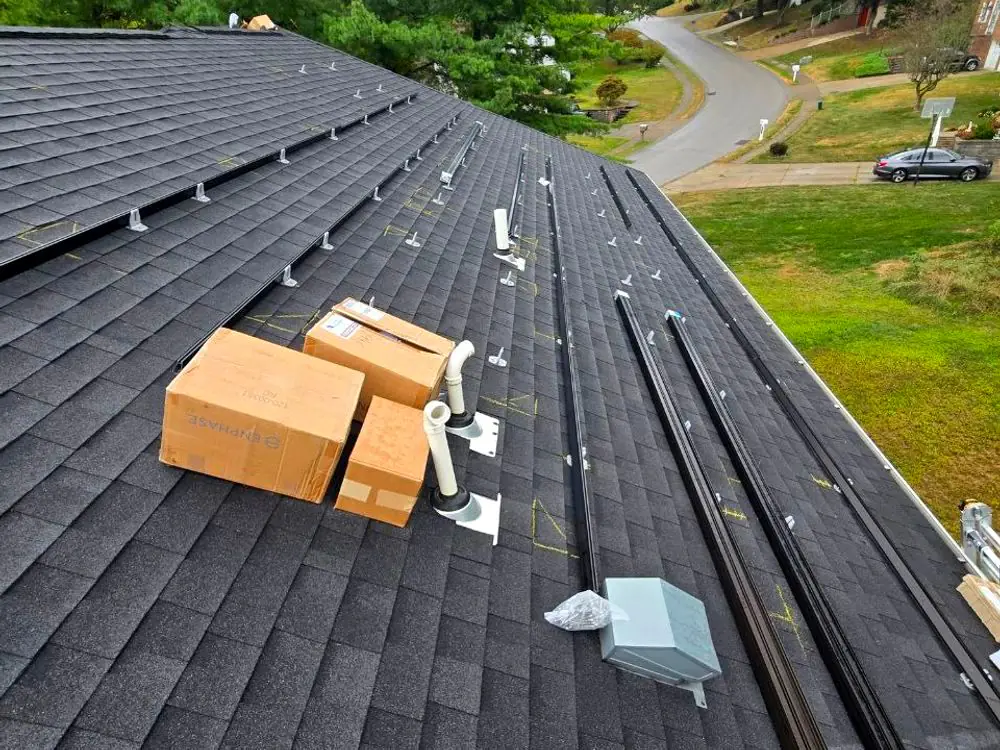 Mounting rails and flashings set out on a shingle roof before the modules go on
