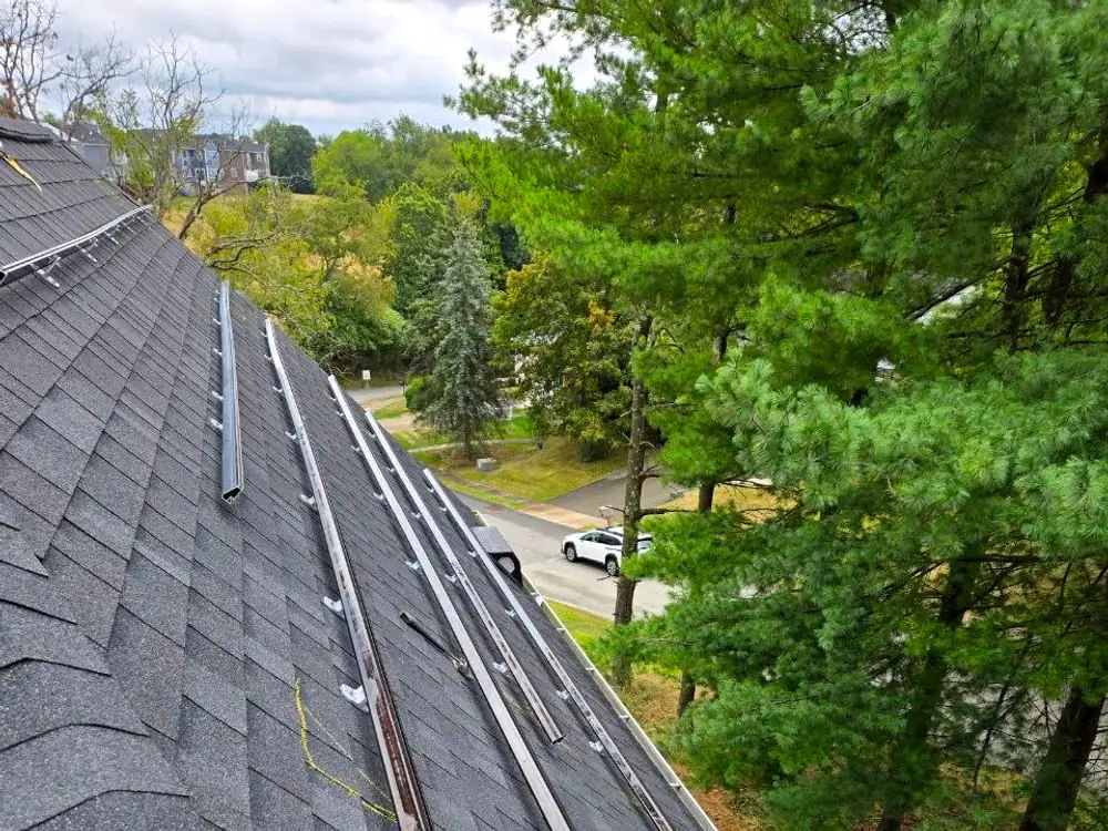 Mounting rails and flashings fixed along a shingle roof plane before the modules are set