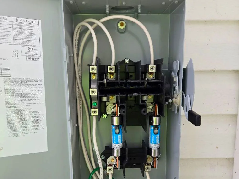 A fused service disconnect opened for testing, with the switch blades and conductors visible